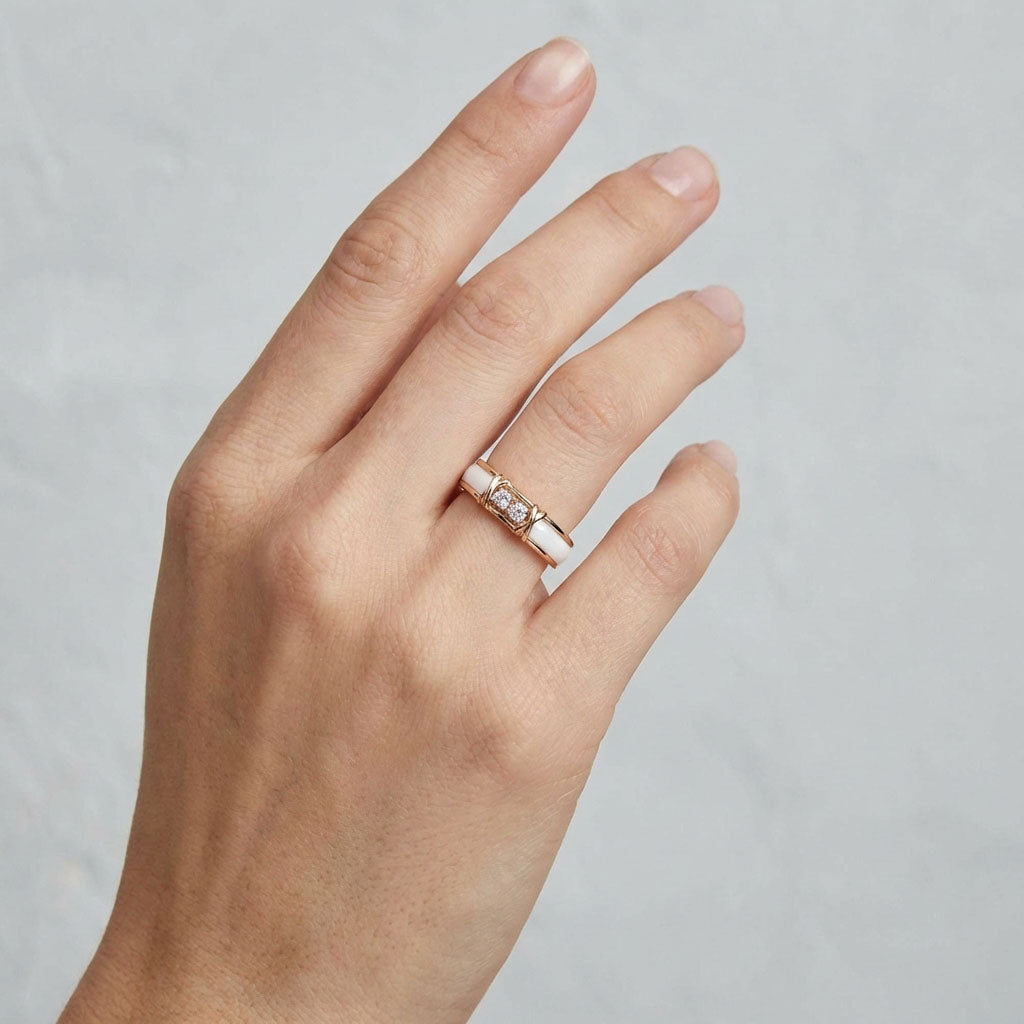 Gold-tone ring with white ceramic and two crystals worn on a woman's finger