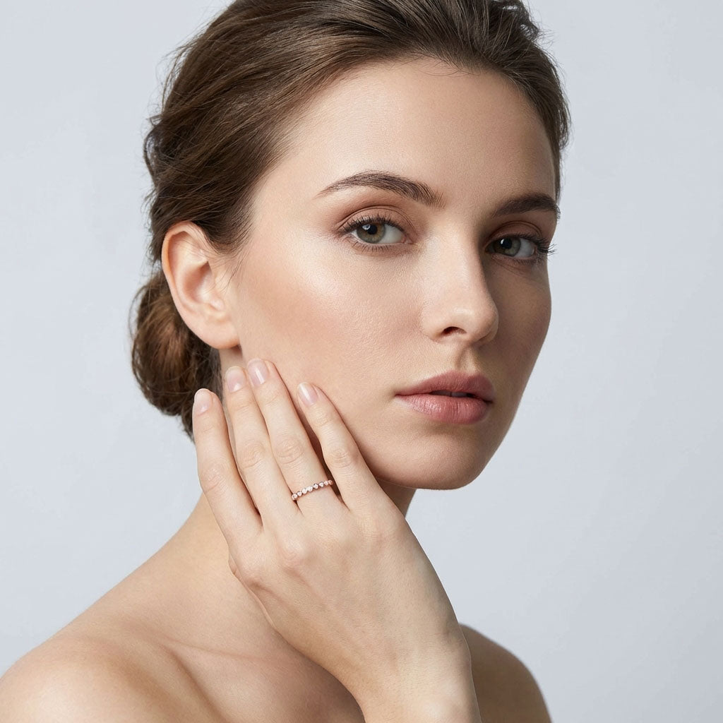 Model touching her cheek, wearing a slim gold-plated ring with white enamel flowers