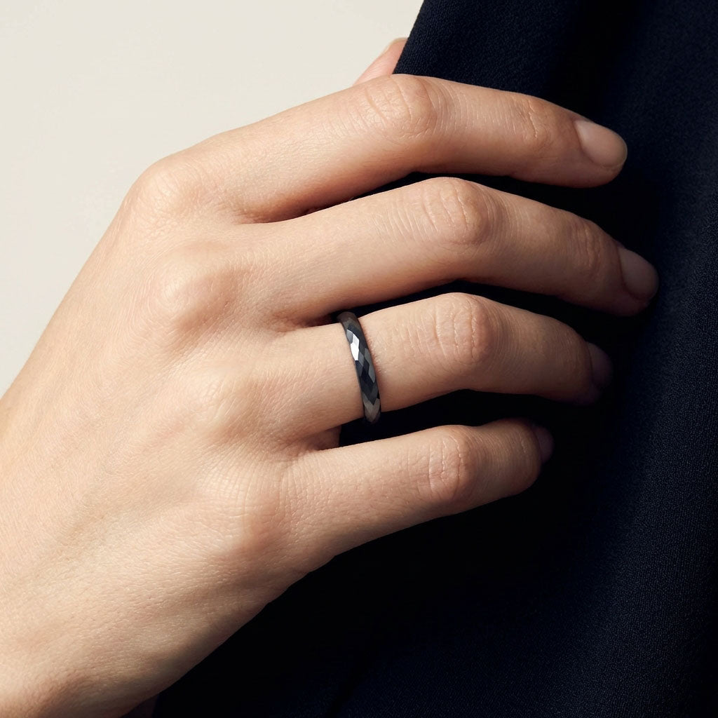 Thin black faceted ceramic ring on a model's finger