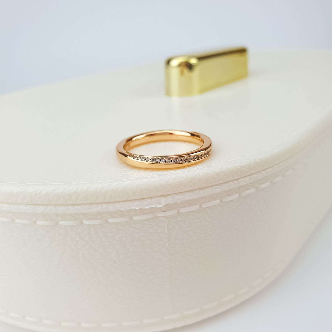 Close-up of a gold-plated cubic zirconia ring on a cream jewellery box