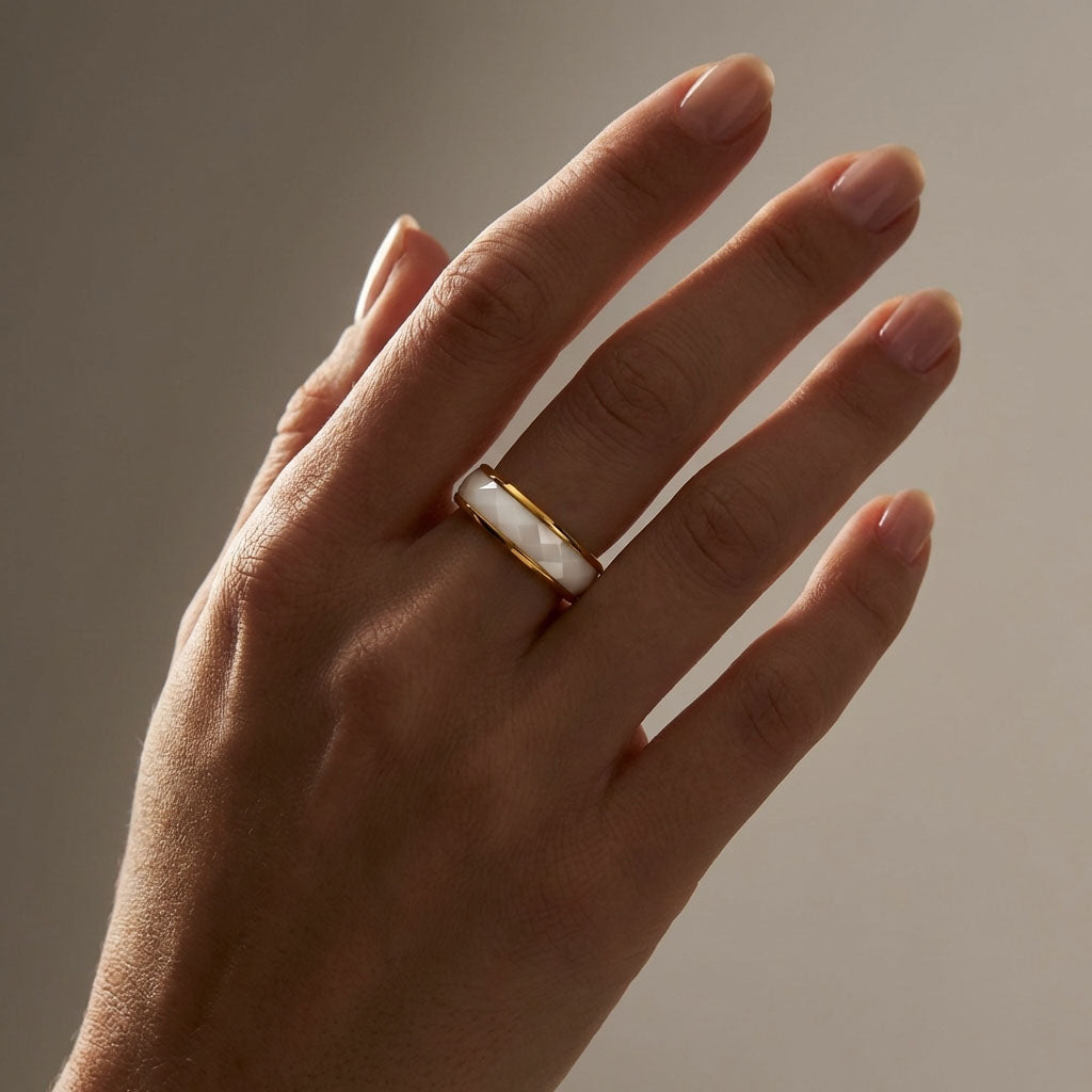 Faceted white ceramic ring with gold-tone edges on a woman's finger