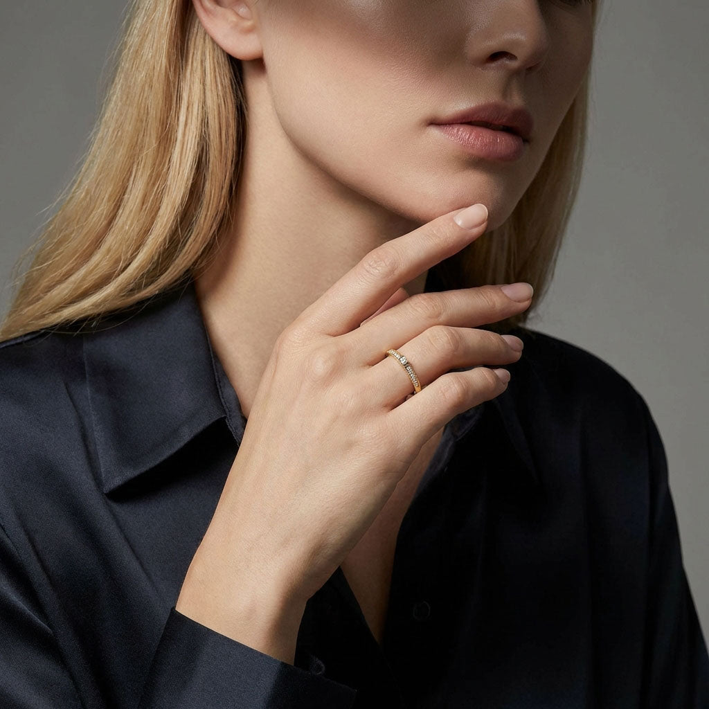 Gold-plated cubic zirconia ring on a model's finger against a dark silk shirt