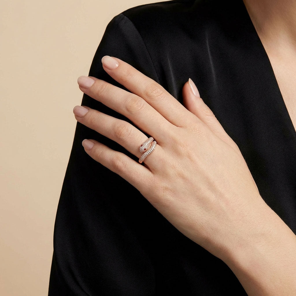 Gold-plated snake ring on a model's ring finger against a black dress