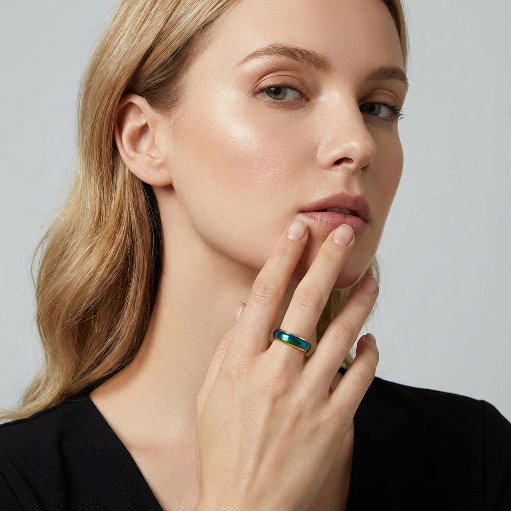 Woman wearing a mood ring with a blue green surface and gold-plated rim
