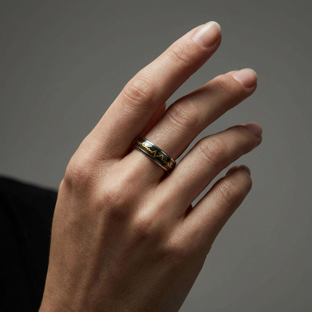 Dark mood ring with a golden heartbeat pattern worn on a man's hand