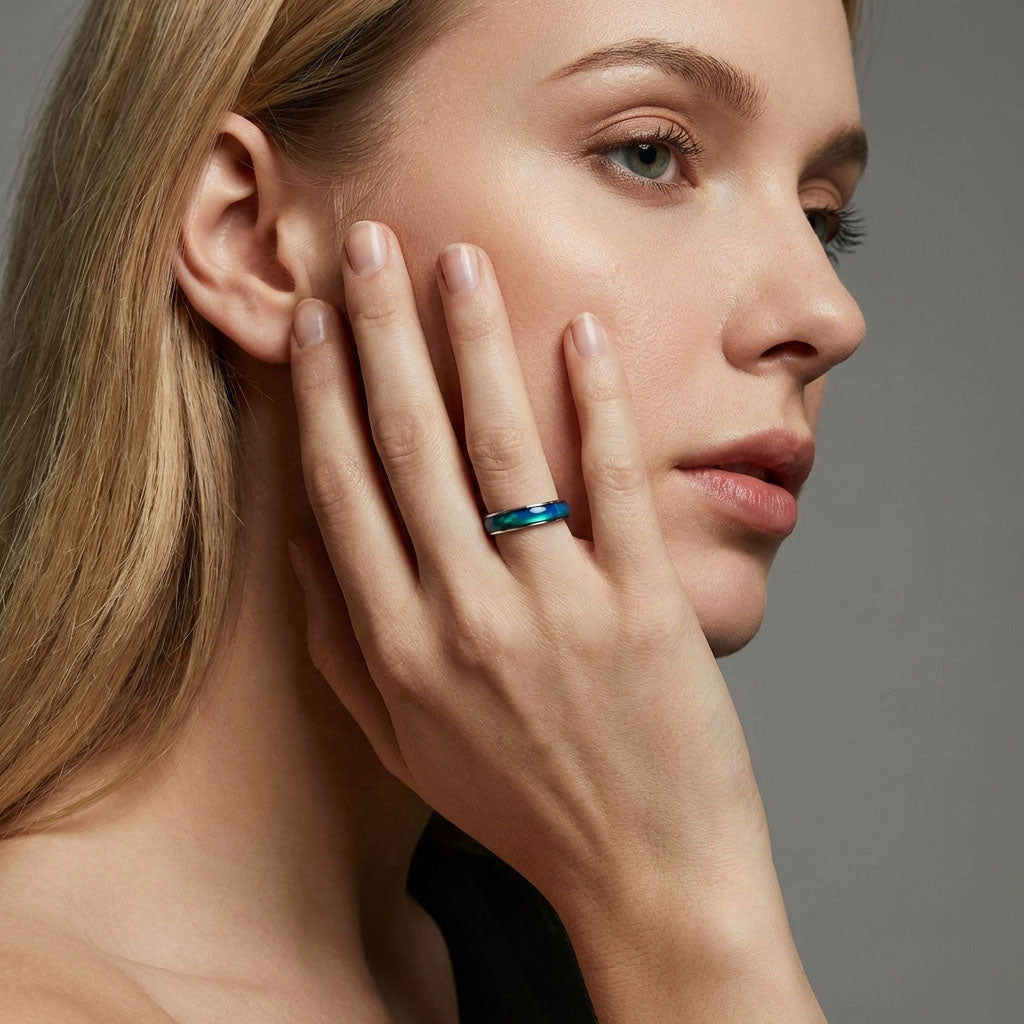 Model touching her cheek, a blue and green mood ring on her finger