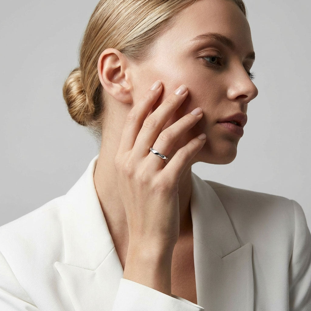 Woman in a white jacket wearing a wavy shiny steel ring