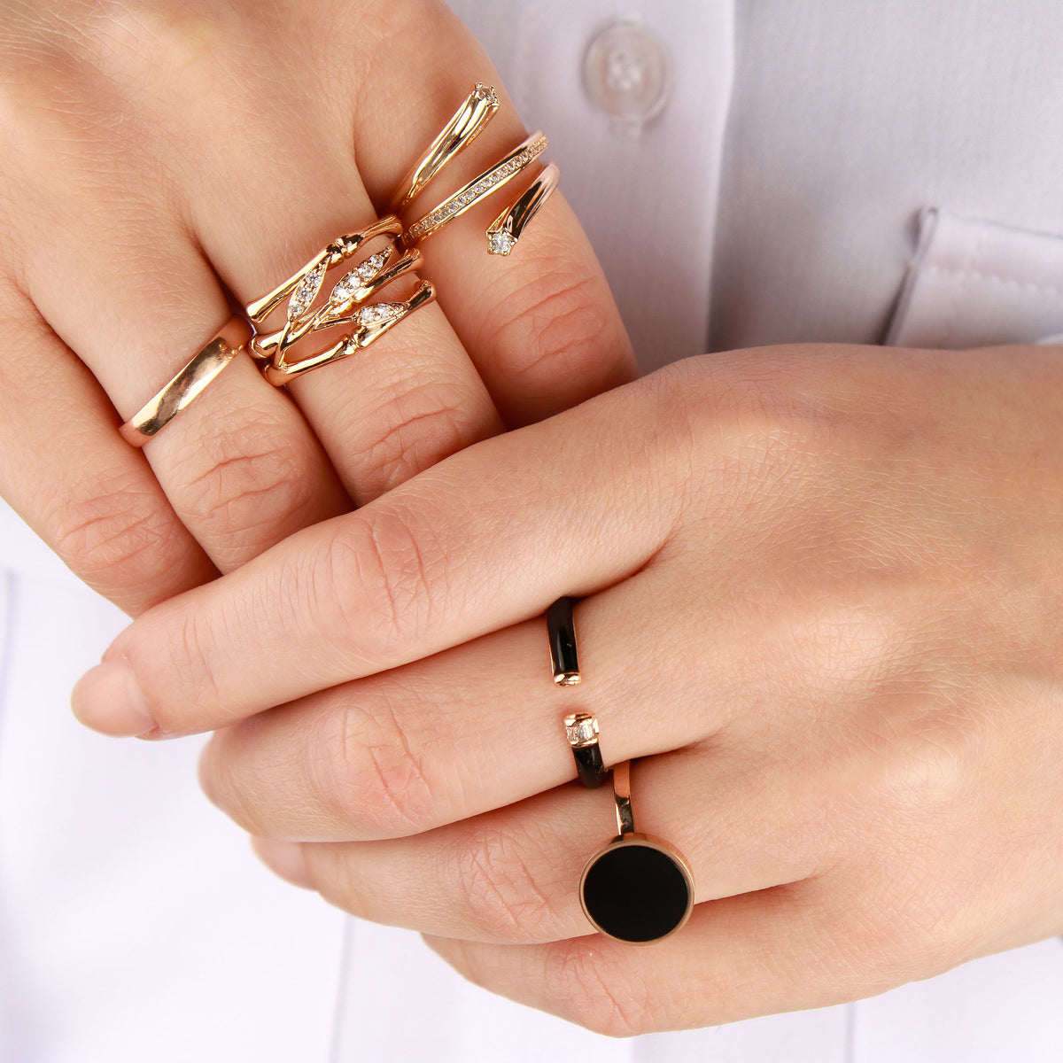 Crossed hands with several gold-tone rings, the leaf ring in the centre