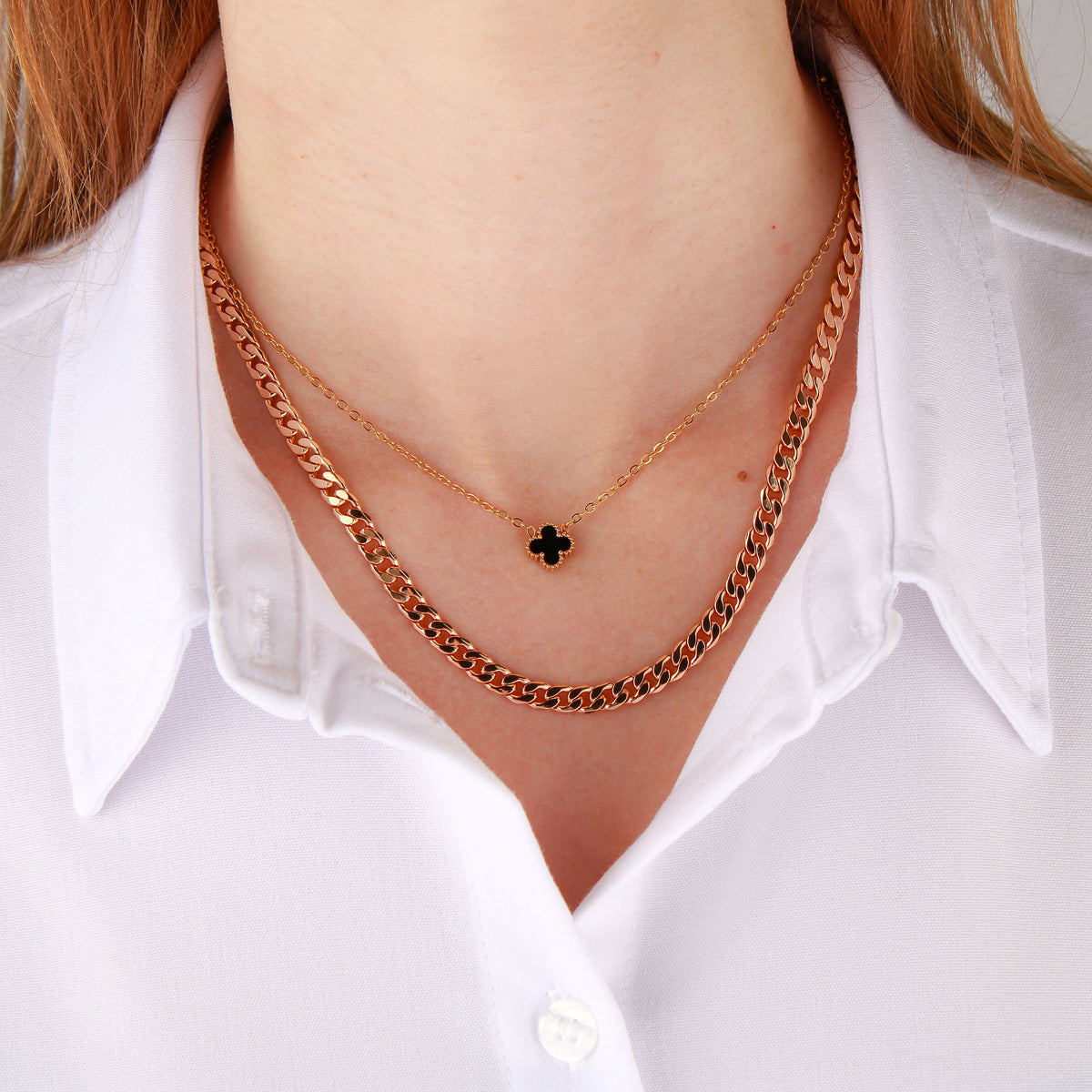 Gold-plated curb chain layered with a fine chain over a white shirt