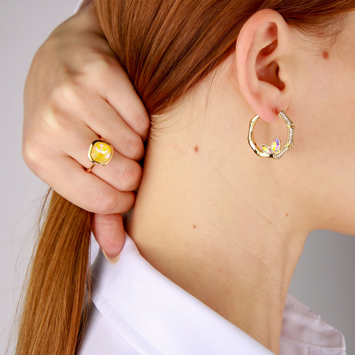 Young woman wearing a crystal hoop earring and a yellow stone ring