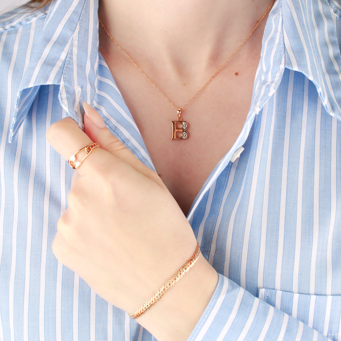Woman in a blue striped shirt wearing a fine chain with a letter pendant