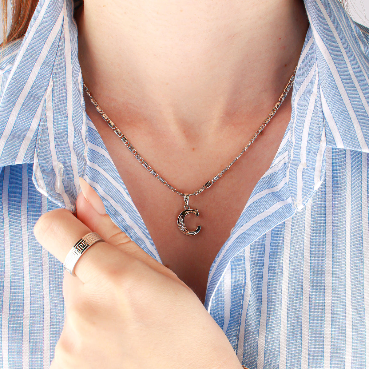 Shiny silver-tone bird's eye chain on a model's neck with a letter pendant