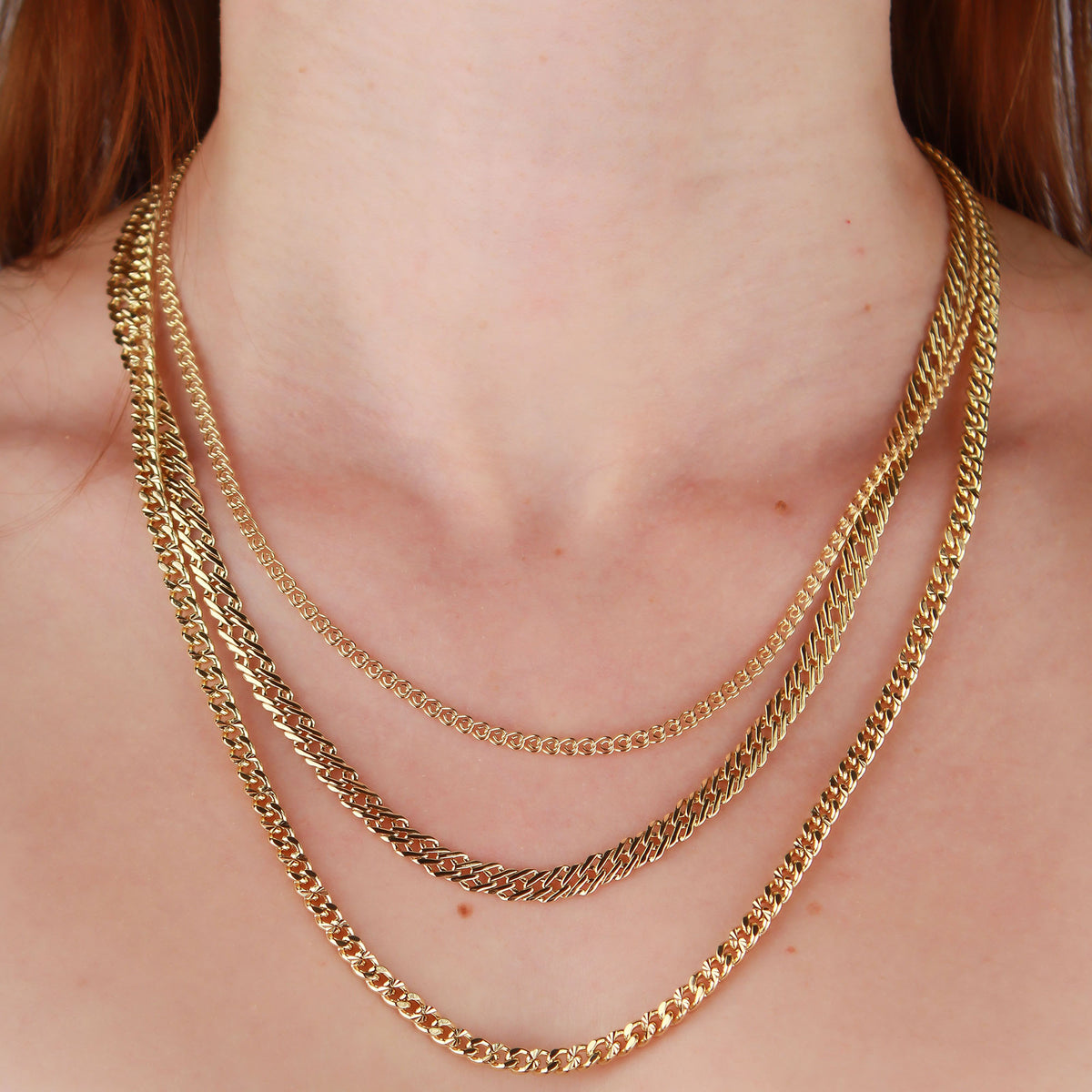 Model wearing three gold-plated chains of different weaves, Nonna chain on top