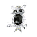 Silver-tone owl brooch with faceted black stone and green accents on a branch