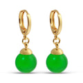 Gold-plated small hoop earrings with bright green beads, close-up on white