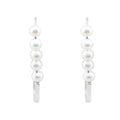 Silver-tone earrings with a row of five white faux pearls on a white background