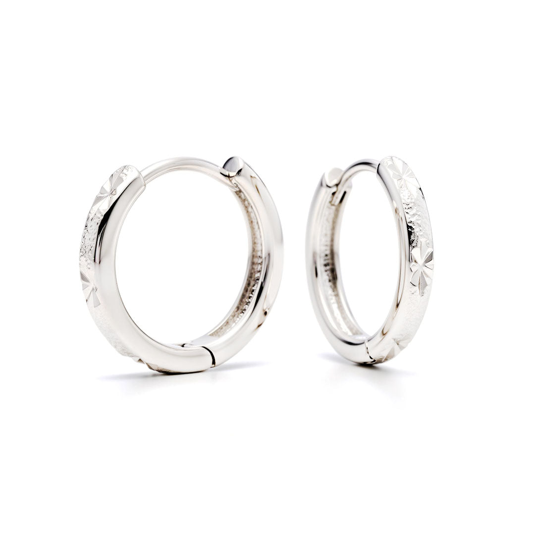 Pair of star-engraved hoop earrings with platinum plating on a white background