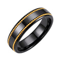 Black ceramic ring with two twisted gold-plated accents on a white background