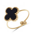 Adjustable ring with a black four-leaf clover in a beaded gold-tone rim