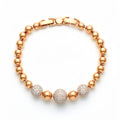 Gold-tone bracelet of smooth beads with three cubic zirconia-covered balls on white